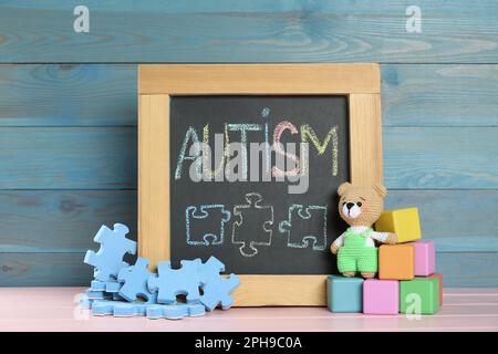 Petit tableau noir avec mot autisme et jouets sur table en bois rose Banque D'Images