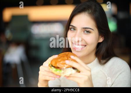 Bonne femme prête à manger burguer dans un restaurant regardant la caméra Banque D'Images