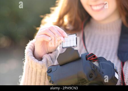 Gros plan sur un photographe insérant une carte dans un appareil photo reflex numérique en hiver Banque D'Images
