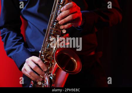 Homme avec saxophone sur fond sombre, gros plan Banque D'Images