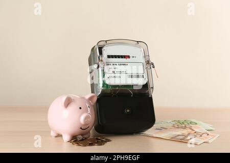 Compteur d'électricité, porcheries et argent sur table en bois Banque D'Images