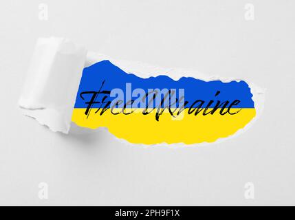 Ukraine libre. Drapeau ukrainien avec phrase, vue à travers un livre blanc déchiré Banque D'Images