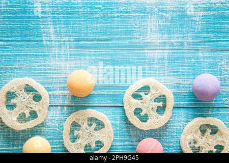 Bombes de bain multicolores et loofahs sur fond bleu en bois. Banque D'Images