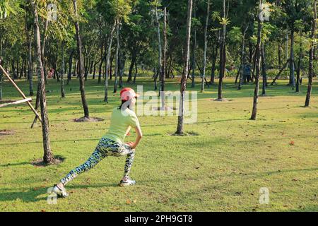 Femme sportive faisant de l'exercice matinal dans le Sunshine Park Banque D'Images