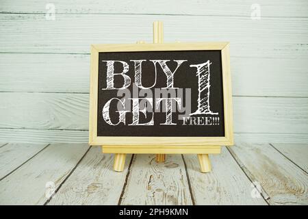 Acheter 1 obtenir 1 message texte libre écrit sur tableau noir debout sur fond en bois Banque D'Images