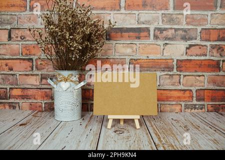 Maquette de carte vide en papier vierge sur chevalet en bois avec bouquet de fleurs séchées Banque D'Images