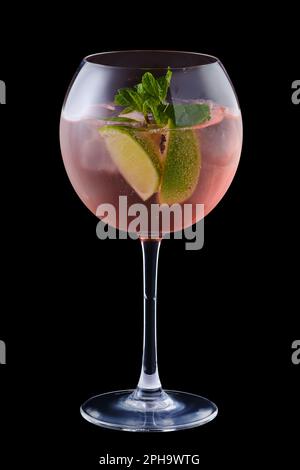 Sangria froide avec de la chaux et de la menthe dans un verre de vin isolé sur fond noir Banque D'Images