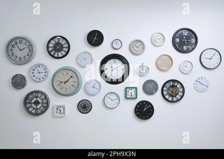 Collection de différentes horloges accrochées au mur blanc Banque D'Images