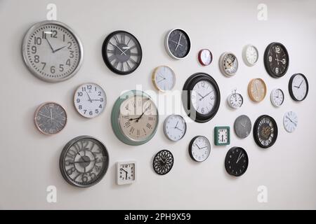 Collection de différentes horloges accrochées au mur blanc Banque D'Images