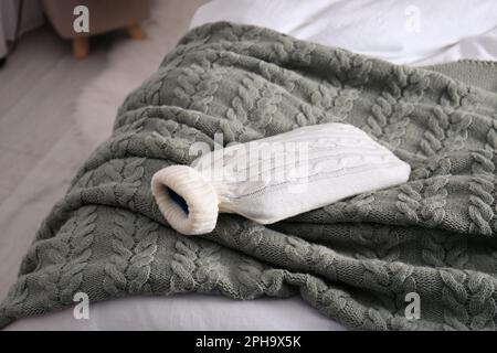 Bouteille d'eau chaude avec couverture tricotée sur le lit à l'intérieur Banque D'Images