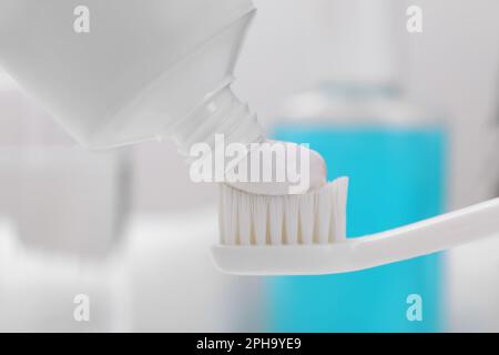 Presser la pâte sur la brosse à dents sur un fond flou, gros plan Banque D'Images