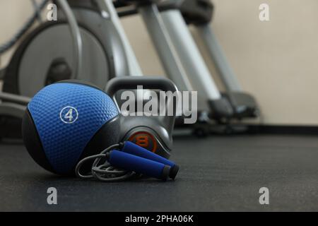 Ballon de médecine bleu, kettlebell et corde à sauter sur le sol dans la salle de gym, espace pour le texte Banque D'Images