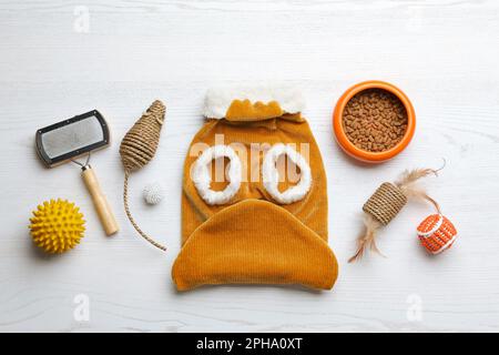 Composition de la couche plate avec vêtements, nourriture et accessoires pour chat sur table en bois blanc Banque D'Images