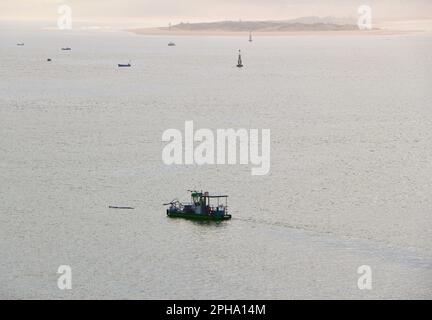 Petit bateau à ponton jumeau de la compagnie de nettoyage de surface d'eau Urbaser dans la baie de Santander Cantabria Espagne printemps matin avec de petits bateaux Banque D'Images