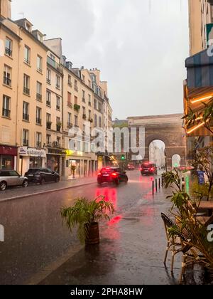 Une scène urbaine par temps pluvieux avec l'arche triomphale de la porte Saint-Denis visible Banque D'Images