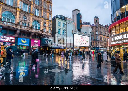 Les gens qui marchent et les magasins réflexions sur la chaussée humide, Leicester Square, West End, Londres, Angleterre, ROYAUME-UNI Banque D'Images