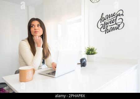 Une jeune femme assise à un bureau avec son ordinateur portable devant elle Banque D'Images