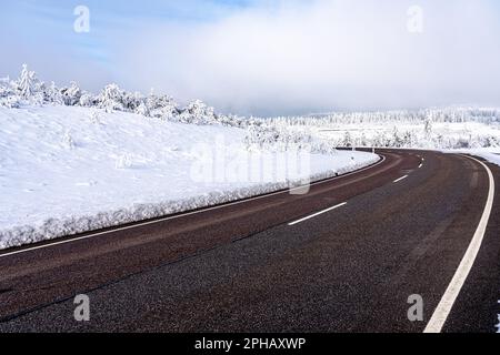 Une scène d'hiver pittoresque avec une route sinueuse située au bas d'une colline Banque D'Images