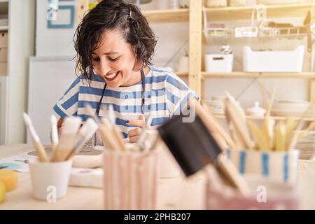 Femme souriant tout en faisant de l'artisanat d'argile dans une classe de poterie. Artisanat, art et passe-temps. Banque D'Images