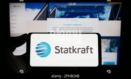 Personne tenant un téléphone portable avec le logo de la société norvégienne d'hydroélectricité Statkraft COMME à l'écran devant la page web d'affaires. Mise au point sur l'affichage du téléphone. Banque D'Images