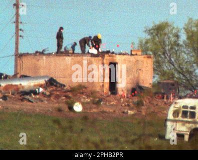 Waco, Texas, États-Unis, 21 avril 1993 : des agents fédéraux chargent des corps dans des sacs de corps sur le dessus du bunker de l'enceinte de la branche Davidienne deux jours après un incendie dévastateur qui a tué 76 membres qui ont été enfermées dans la propriété du culte religieux et ont mis fin à une confrontation de 51 jours avec les organismes fédéraux d'application de la loi. ©Bob Daemmrich Banque D'Images