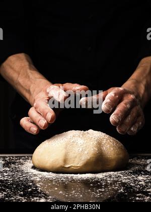 Boulanger ou cuire pétrir une pâte de levure biologique, fond noir avec espace pour votre texte ou image, main-d'oeuvre traditionnelle dans la cuisine Banque D'Images