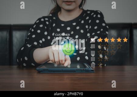 Jeune femme d'affaires en vérifiant la marque et en appuyant sur émoticône visage , enquête de satisfaction de la clientèle sur l'écran tactile de la boîte de liste de contrôle. Évaluation du service client Banque D'Images