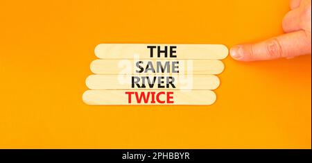 La même rivière deux fois symbole. Concept mots la même rivière deux fois sur bâton de bois. Belle table orange fond orange. Motivation des affaires les s Banque D'Images