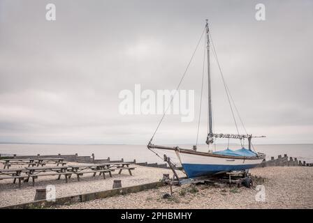 Un voilier sur la plage de galets de Whitstable, sur la côte du Kent, au Royaume-Uni. Banque D'Images