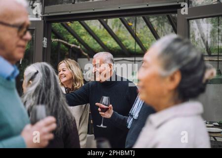 Heureux homme mature appréciant avec des amis hommes et femmes senior pendant le dîner à l'arrière-cour Banque D'Images