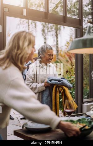 Bonne femme âgée portant des foulards pendant le dîner Banque D'Images