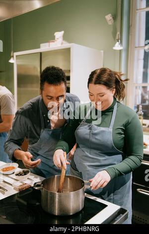 Les élèves de sexe masculin et féminin préparent la nourriture pendant les cours de cuisine dans la cuisine Banque D'Images