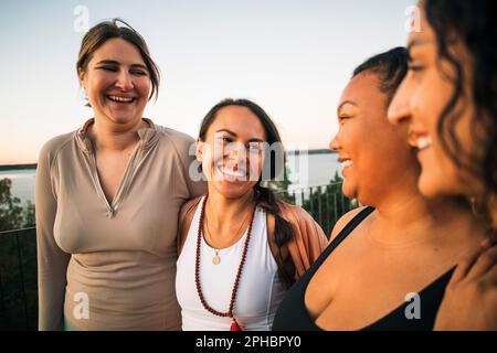 Des amies multiraciales joyeuses rient ensemble au coucher du soleil Banque D'Images