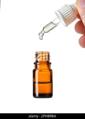 Huile essentielle tombant du compte-gouttes en verre dans un flacon marron isolé sur blanc Banque D'Images
