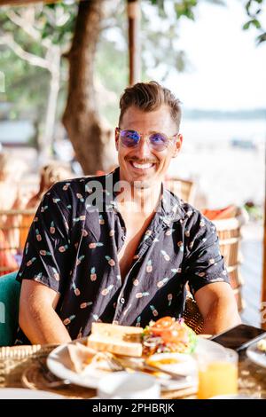 Portrait d'un homme souriant avec petit déjeuner à table au Resort pendant la journée ensoleillée Banque D'Images