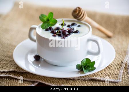 Porridge de semoule de lait cuit avec baies et miel dans une assiette, sur une table en bois. Banque D'Images