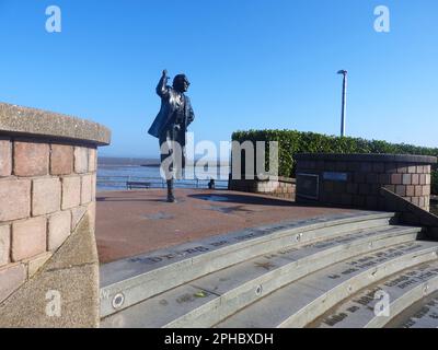 La statue d'Eric Morecambe (Eric Bartholomew. 1926–1984) de l'ancienne comédie due Morecambe et Wise. Il se trouve sur le front de mer à Morecambe, dans le Lancashire, au Royaume-Uni, au sommet d'un ensemble de marches gravées avec les mots de la paire signature Tune 'Bring Me Sunshine' gravés dans une police de type machine à écrire. Elle a été sculptée par Graham Ibbeson et dévoilée par feu la reine Elizabeth II en juillet 1999. Il se trouve non loin de la célèbre tour de 1905 horloge Tour de l'horloge. Conçu par Cressey et Keighley construit en brique rouge avec bandes et pansements de grès. Banque D'Images