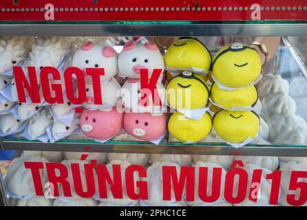 Armoires en verre chauffées pleines de bouchées de banh Bao cuites à la vapeur sucrées vietnamiennes en forme de porc de peppa et d'un Minion à vendre sur le marché central de Pleiku i. Banque D'Images