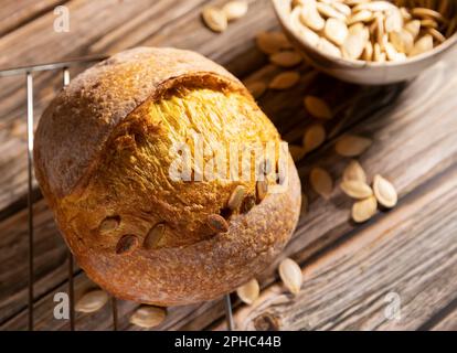 Pain; pain au levain traditionnel; forme ronde avec graines de citrouille sur fond rustique en bois. Le concept des méthodes traditionnelles de cuisson sans levure Banque D'Images