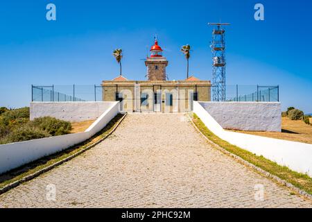 Phare clôturé de Farol da Ponta da Piedade à Lagos capturé de l'allée lors d'une journée ensoleillée avec ciel bleu, présentant sa tour et porte. Banque D'Images