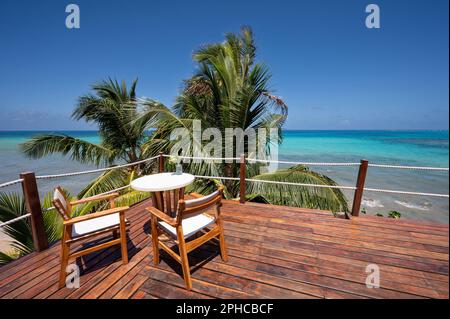 Table de café avec chaise sur fond de mer tropicale. Terrasse en bois vide en bord de mer Banque D'Images