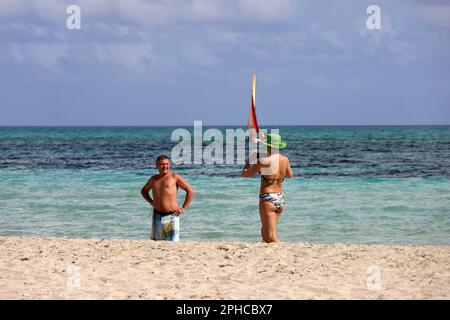 Femme photographiant un homme par smartphone sur une plage de sable tropical. Photo prise sur la côte océanique, vacances et voyages Banque D'Images