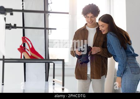 Équipe de photographe professionnel et directrice artistique féminine vérifiant les photos sur photocamera, faisant le contenu photoshoot Banque D'Images