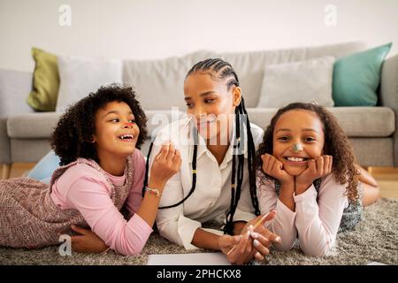 Mummy et filles africaines dessin peinture visages ayant l'amusement à l'intérieur Banque D'Images