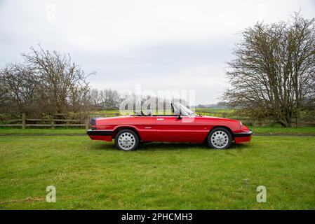 Red Alfa Romeo Spider Series 3 (série 115) garée dans un pré avec le toit en bas Banque D'Images