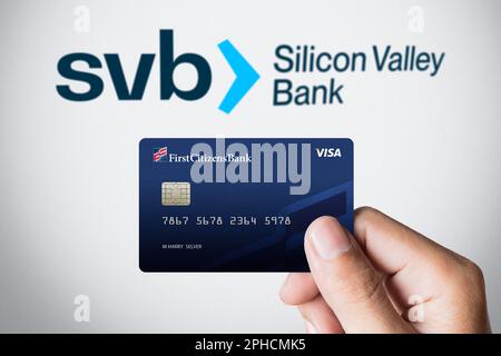 Gros plan tient la main First Citizens Visa Debit Card avant du logo de la Silicon Valley Bank (SVB) en arrière-plan, Qatar, 29 mars 2023. Modification d'illustration Banque D'Images