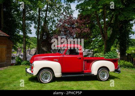 Red 1949 camion de pick-up américain GMC garé sur l'herbe un jour d'été Banque D'Images