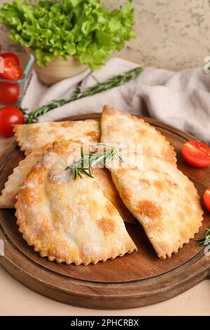 Panneau en bois avec empanadas de viande cuite sur la table, gros plan Banque D'Images