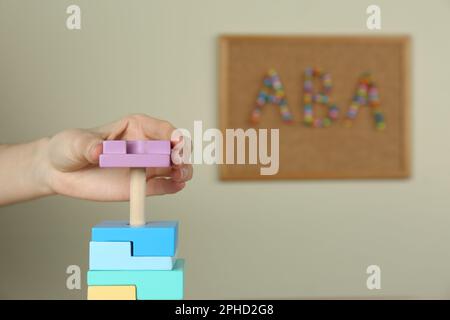 Enfant jouant avec la pyramide des jouets à l'intérieur, gros plan. Concept de thérapie ABA Banque D'Images