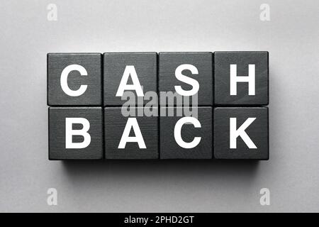 Mot Cashback fait avec des cubes en bois noir sur fond gris, plat Banque D'Images